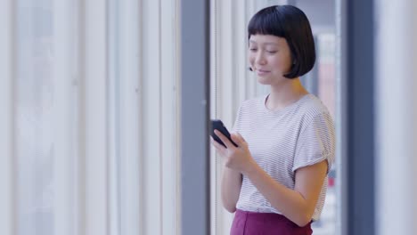 female creative using smartphone in a modern office