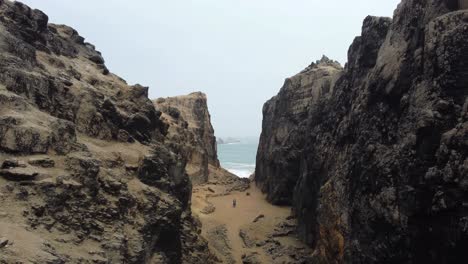 Drone-video-of-a-person-standing-in-mountain-pass-by-a-rocky-beach