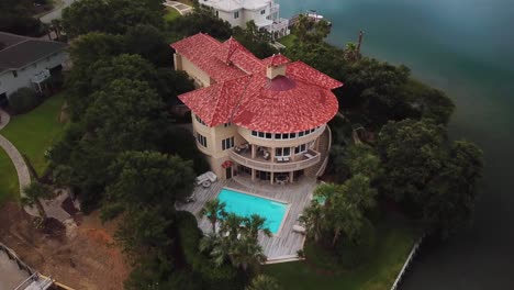 Early-morning-sunrise-drone-flyaway-of-Mediterranean-Spanish-style-red-roof-tile-house-on-figure-eight-island-in-Wilmington-North-Carolina