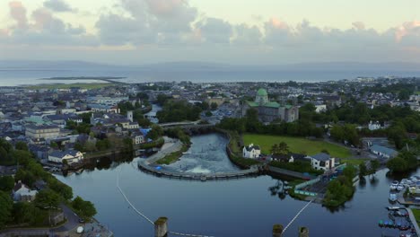 drone ascends above salmon weir on river corrib to establish galway cathedral, city centre and mutton island