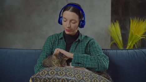 woman in headphones relaxing with cats at home