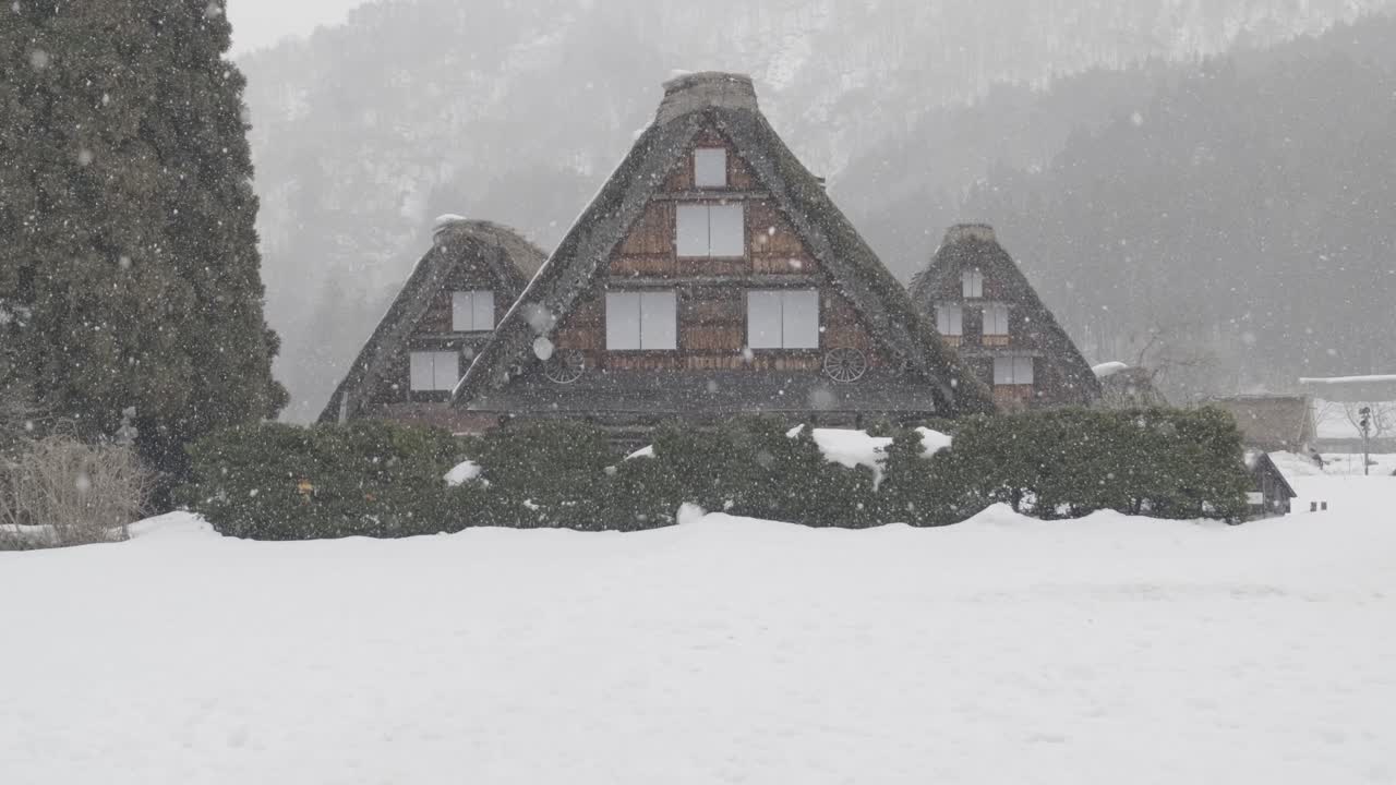 una toma en cámara lenta de tres casas bajo la nieve en el pequeño pueblo de shirakawago durante el invierno en japón