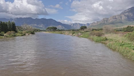 river flowing through a valley, surrounded by mountains and trees