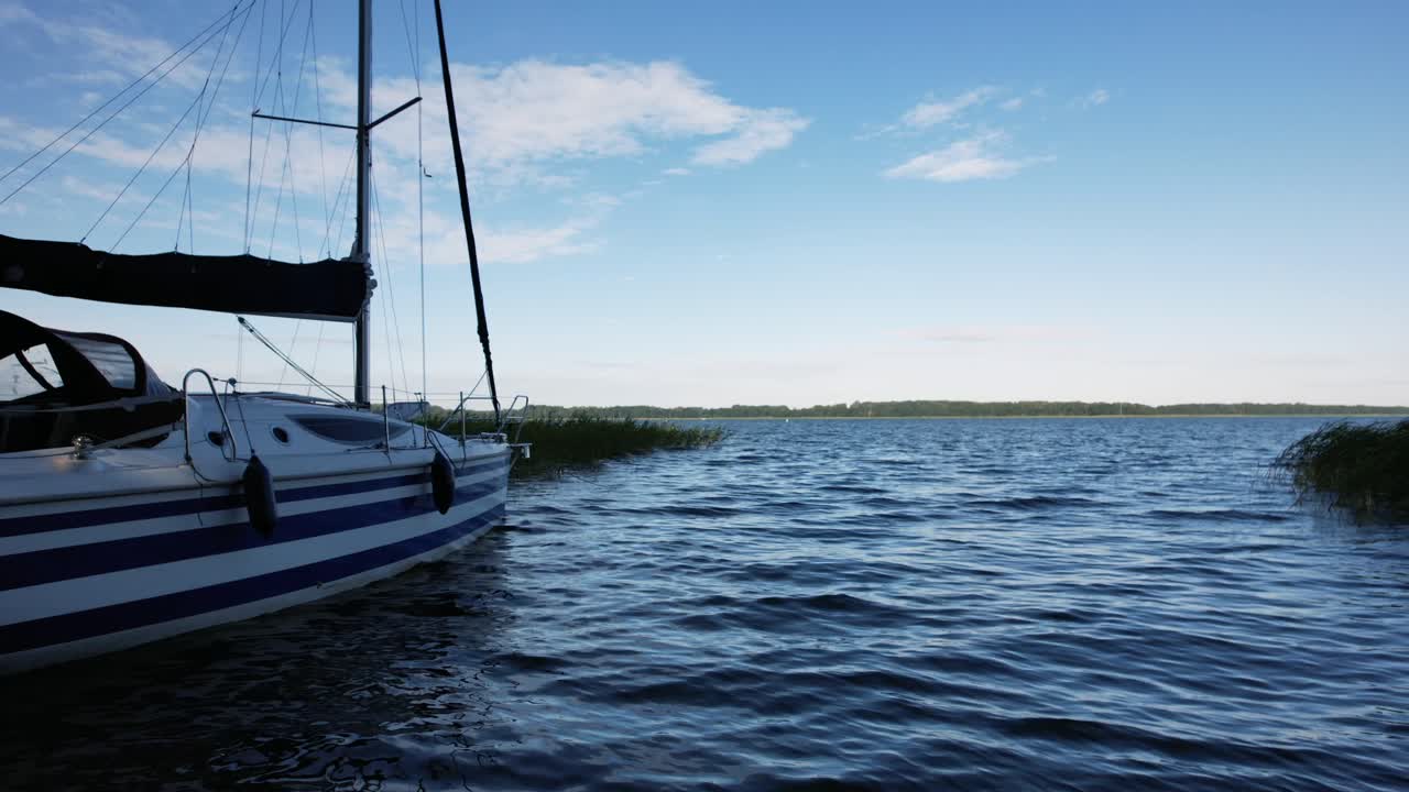 una toma de acercamiento de un yate de lujo navegando en un mar azul profundo cerca de la isla mediterránea al atardecer