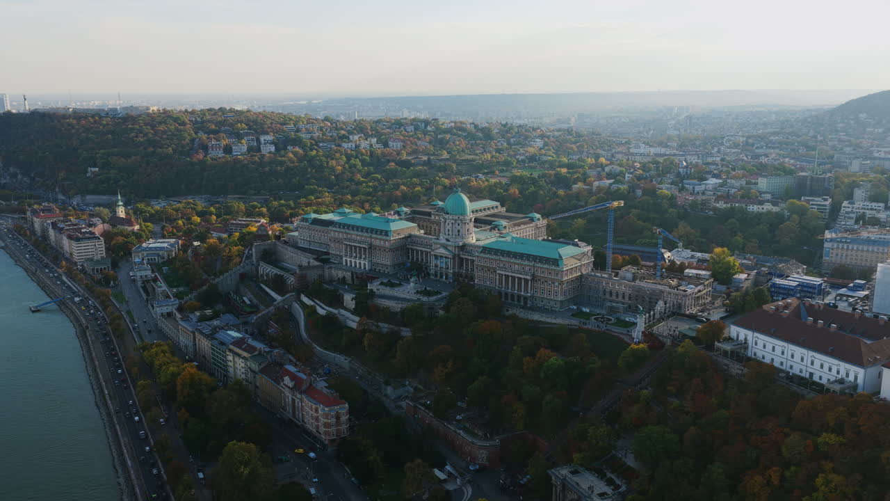Aerial shot of Buda Castle’s grand dome overlooking the Danube, surrounded by the hills and greenery of Budapest