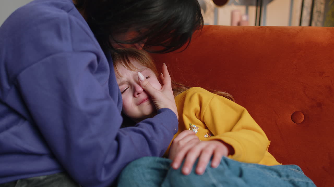 Closeup of sad girl kid is crying and lying on mother at home violence against children in family