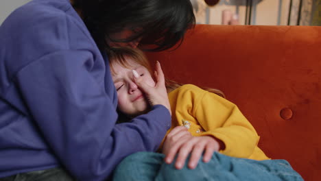 closeup of sad girl kid is crying and lying on mother at home violence against children in family