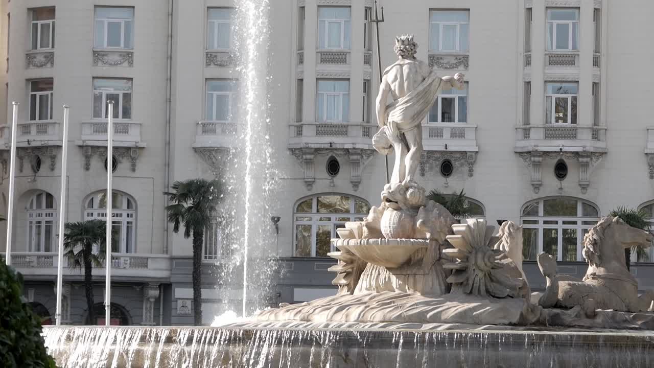 Fountain in front of the Palace Hotel Neptuno in Madrid with statues and water flow
