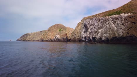 Wide-gimbal-shot-from-a-moving-boat-of-rugged-sea-caves-lining-the-coast-of-Middle-Anacapa-Island-at-Channel-Islands-National-Park-in-the-Pacific-Ocean