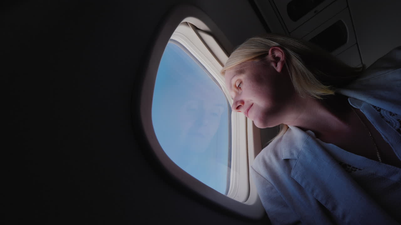 비행기를 타고 창밖을 내다보는 여성의 낮은 각도 viev