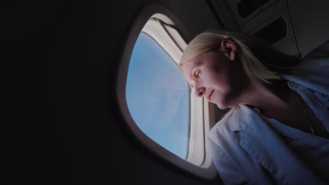 low angle viev of woman flying in an airplane looking out the window