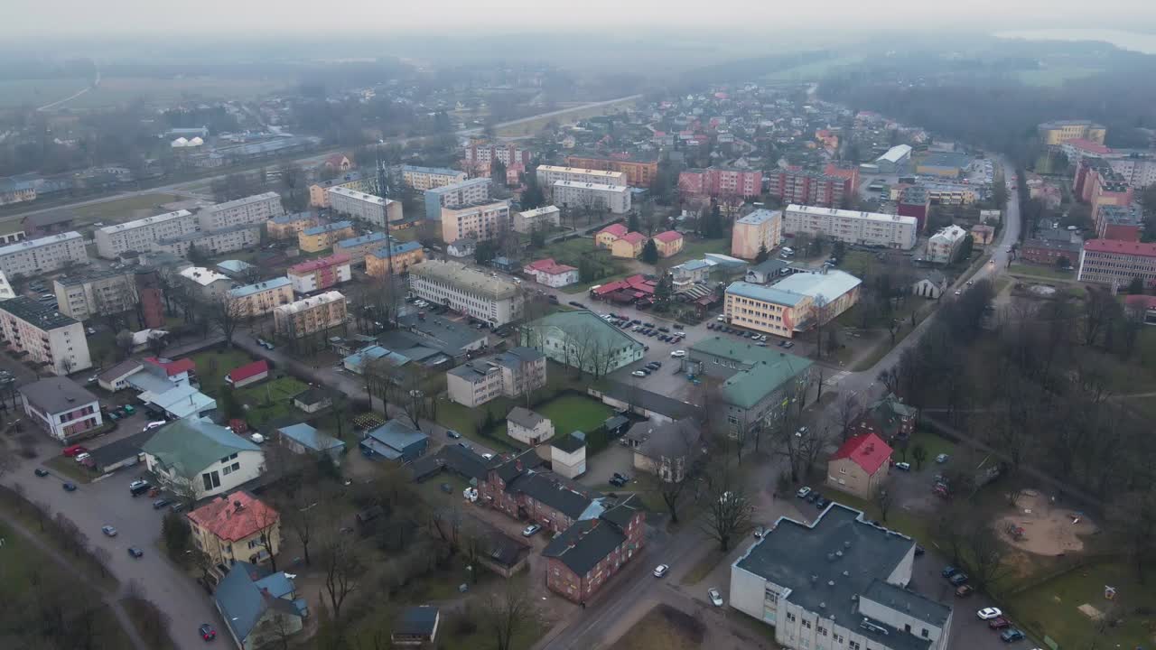 аэрофотографа города балви, купающегося в теплом свете заката, с городскими зданиями, парковками и снежным пейзажем. мирная зимняя сцена.
