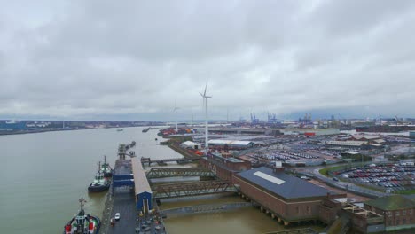 Vista-Panorámica-De-Las-Turbinas-Eólicas-Sobre-El-Sitio-Industrial-Cerca-Del-Puerto-Fluvial-Con-Vistas-A-La-Ciudad