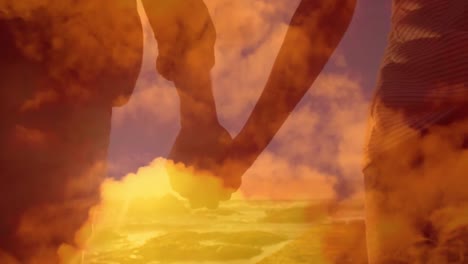 animation of a happy couple holding hands walking on a beach by sea with orange clouds.