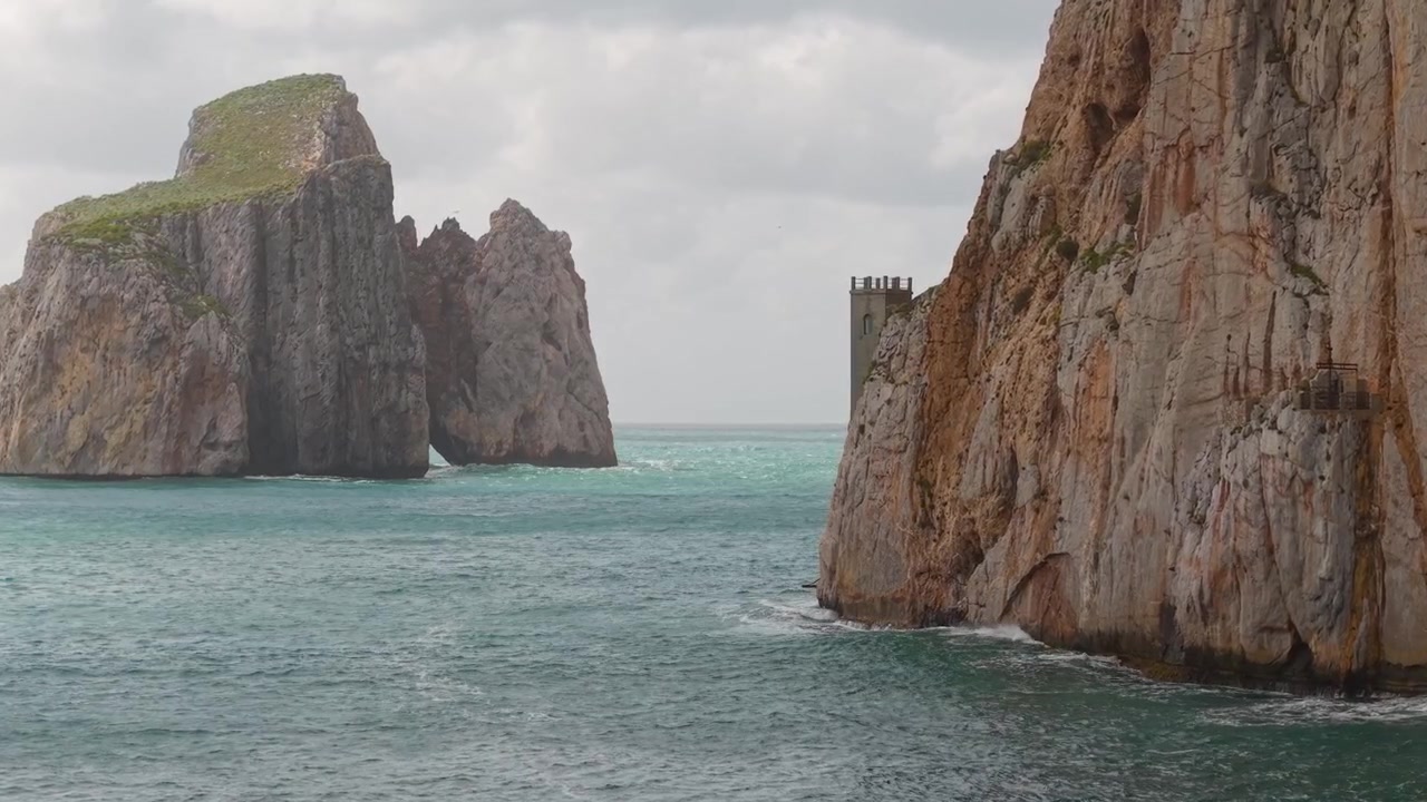 Porto Flavia lungo la costa di Masua in Sardegna, Italia, con il faraglione Pan di Zucchero sullo sfondo. Ripresa aerea.