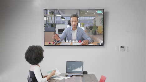 mujer de negocios afroamericana en videollamada con un colega caucásico en la pantalla
