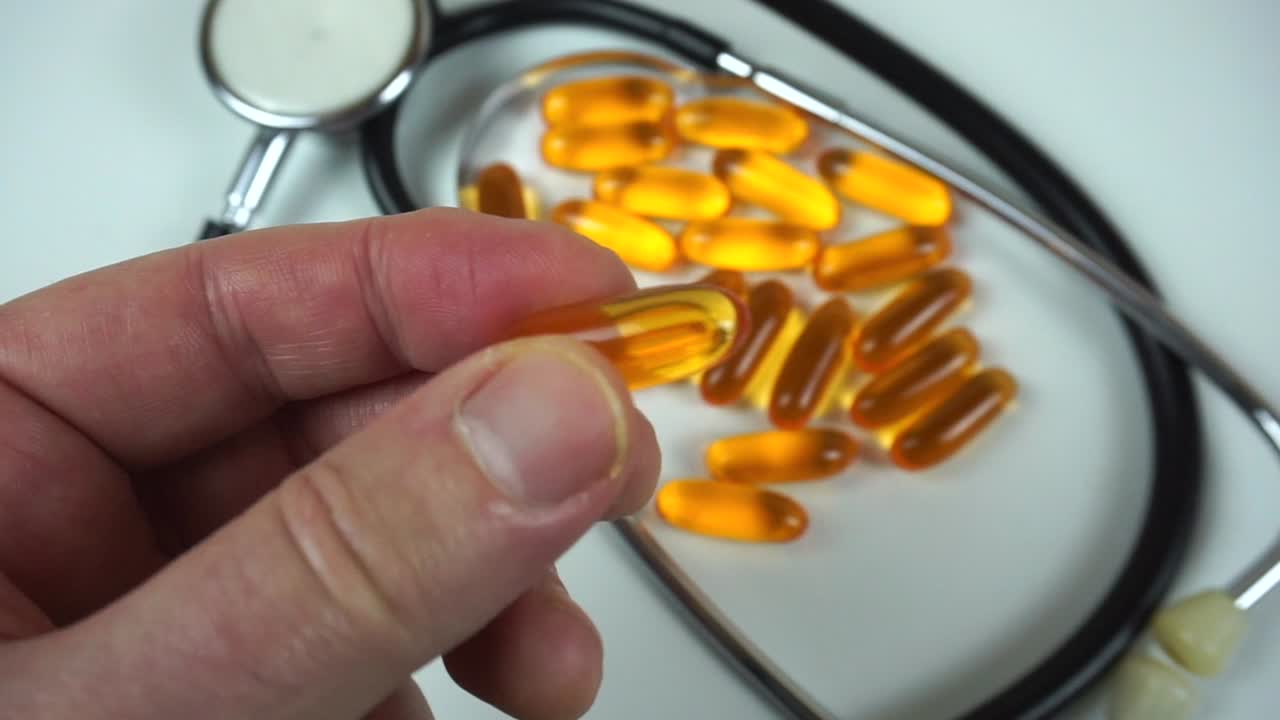 Dokter atau apoteker memegang pil suplemen omega 3 transparan dengan latar belakang putih