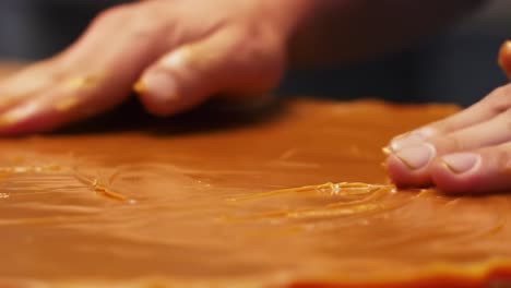 hands skillfully preparing a smooth layer of caramel in a culinary process, focusing on the texture and technique of the crafting method used in dessert making