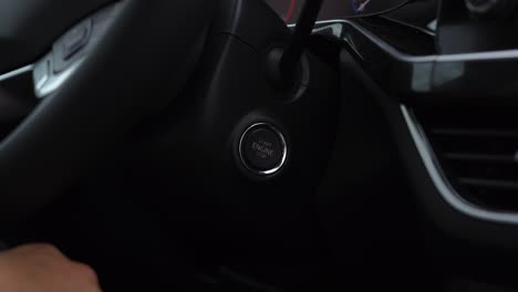 el hombre presiona el botón de arranque y parada con su dedo para arrancar un coche nuevo después de la compra