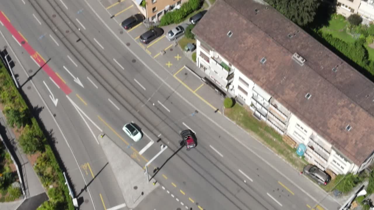 drone de arriba hacia abajo disparado siguiendo un fiat 500 descapotable conduciendo en la carretera de la ciudad en zúrich, suiza