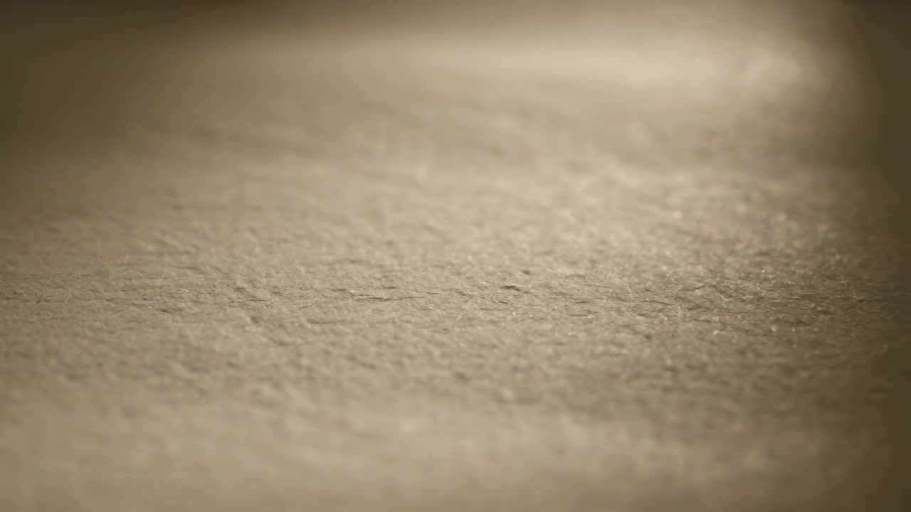 Revealing textured beige sheet sharpening via small camera dolly on table, warm highlight shifting