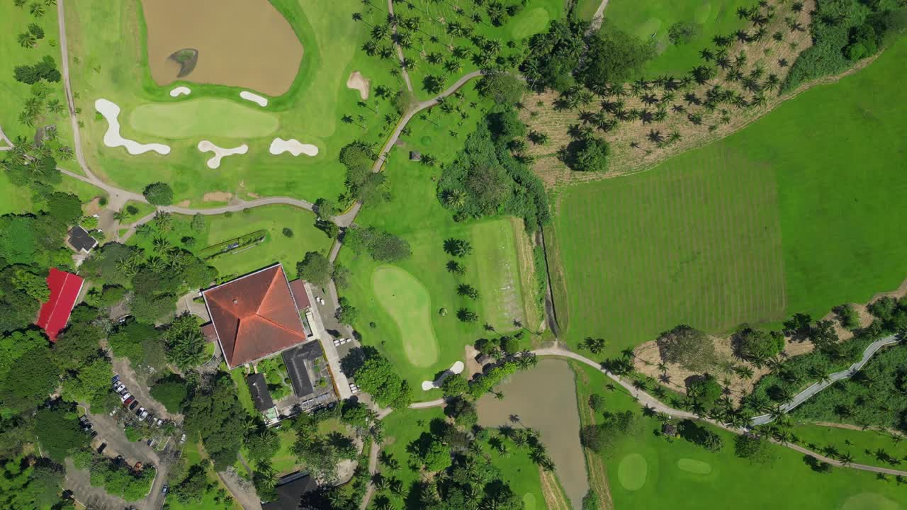 A higher top view aerial showcasing the expansive grounds of Canlubang Golf and Country Club, revealing manicured fairways, brown puddles, and tropical greenery in Calamba Laguna, Philippines