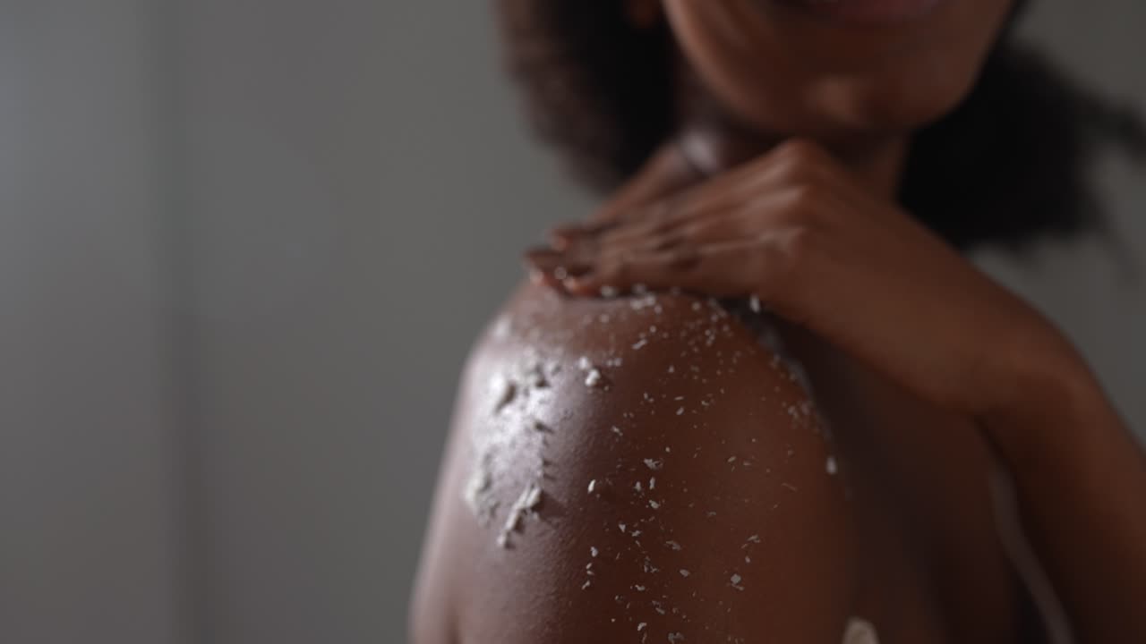mujer aplicando exfoliante corporal al hombro