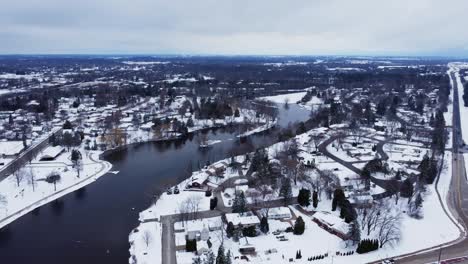 aerial flyover of a suburban neighborhood near a river in winter