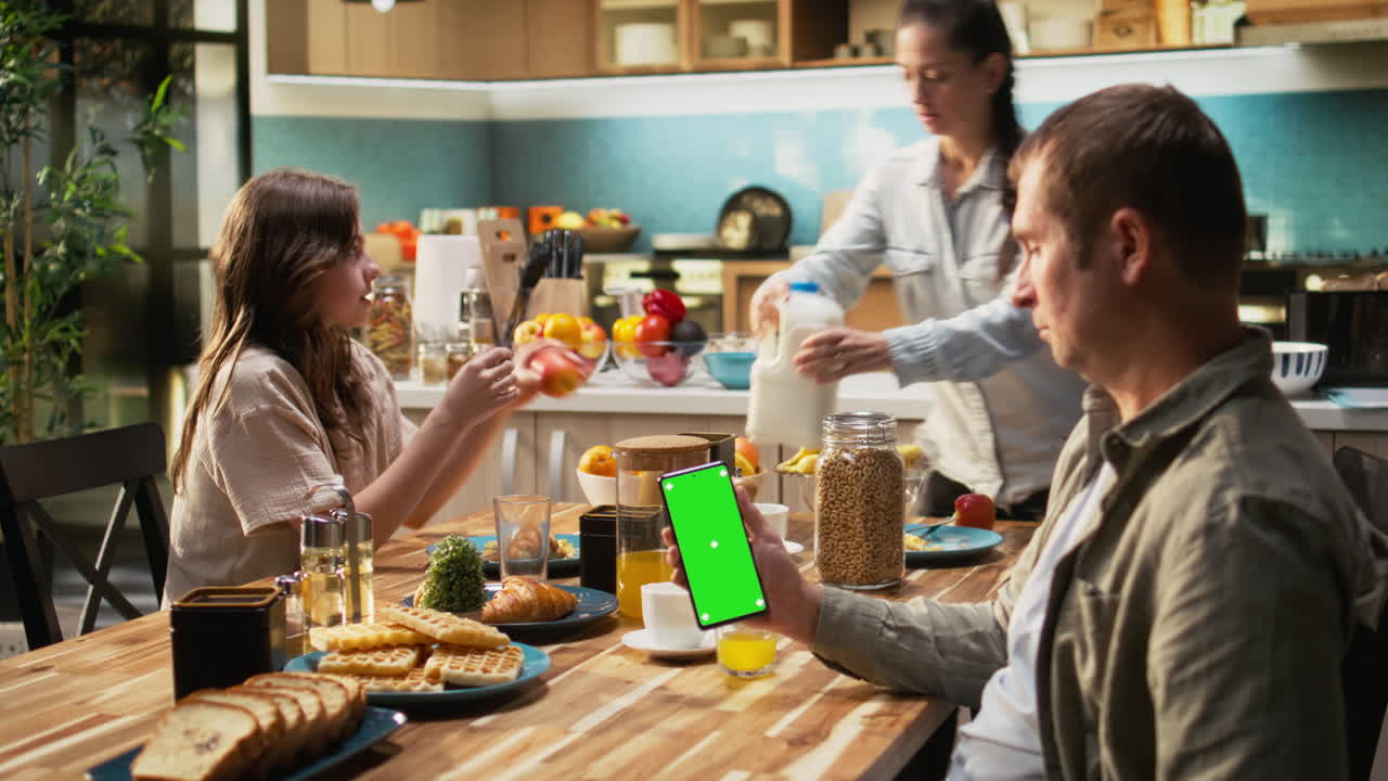 Vertical chroma key on phone next to family enjoying breakfast at the table