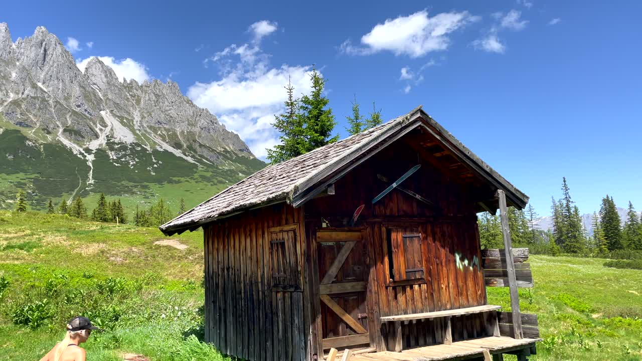 antigua casa de montaña de madera para excursionistas en el idílico paisaje de austria durante la luz del sol - mujer caminando para descansar en la vieja casa de campo