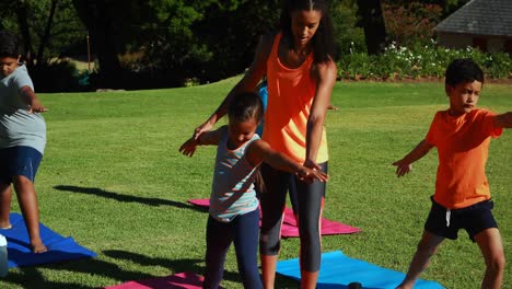 yoga instructor instructing children in performing exercise