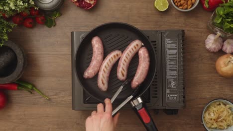 crop person turning homemade sausages frying in pan