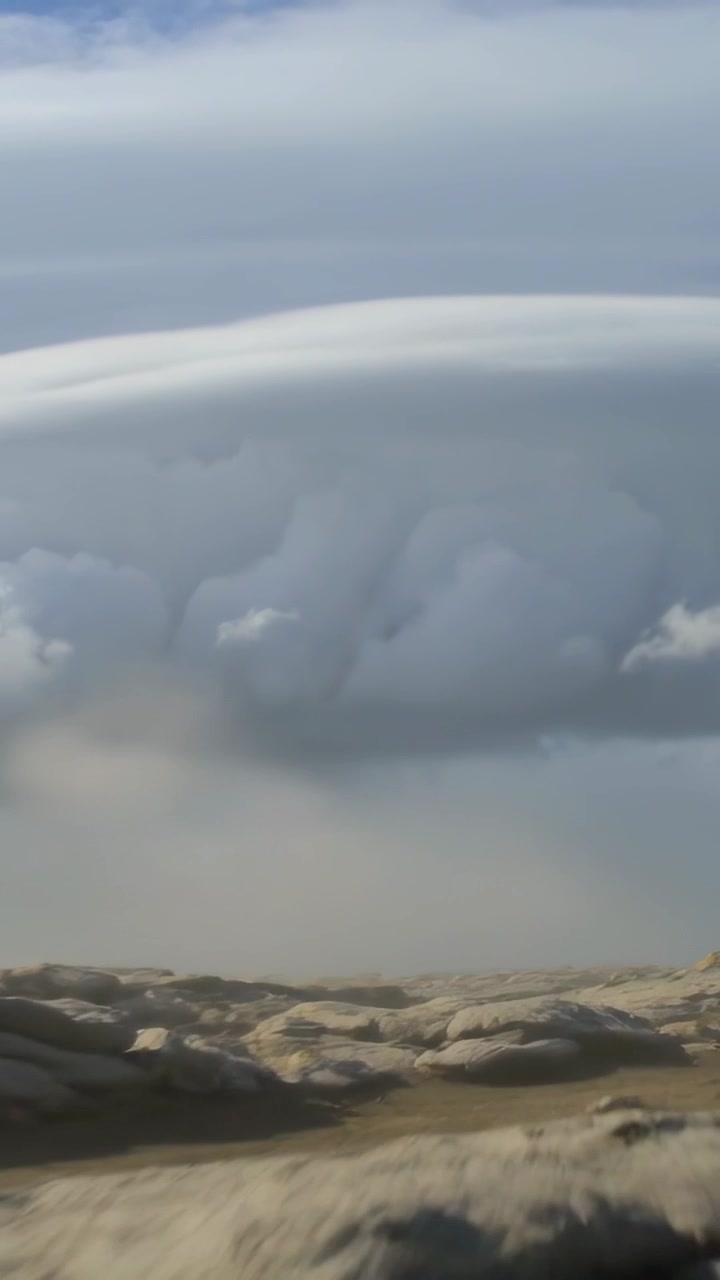 Video vertical: Viento cambiante moviendo nubes bajas, abultándose y enviando lluvia débil sobre rocas costeras.