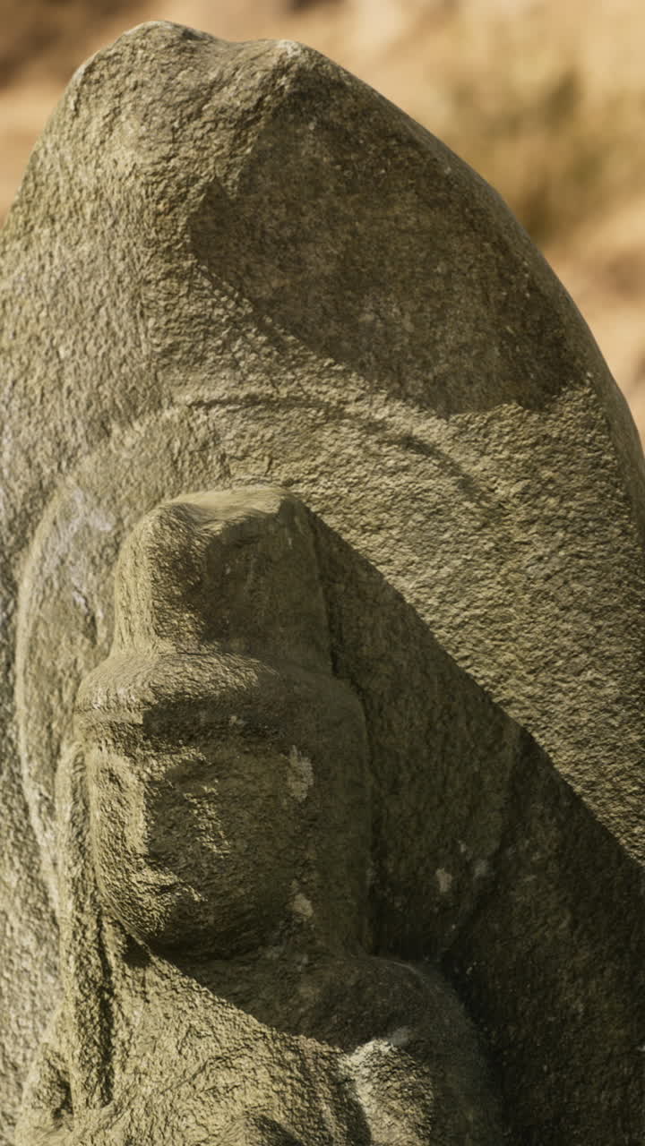 Ancient stone carving amid sand and stones in a dry landscape