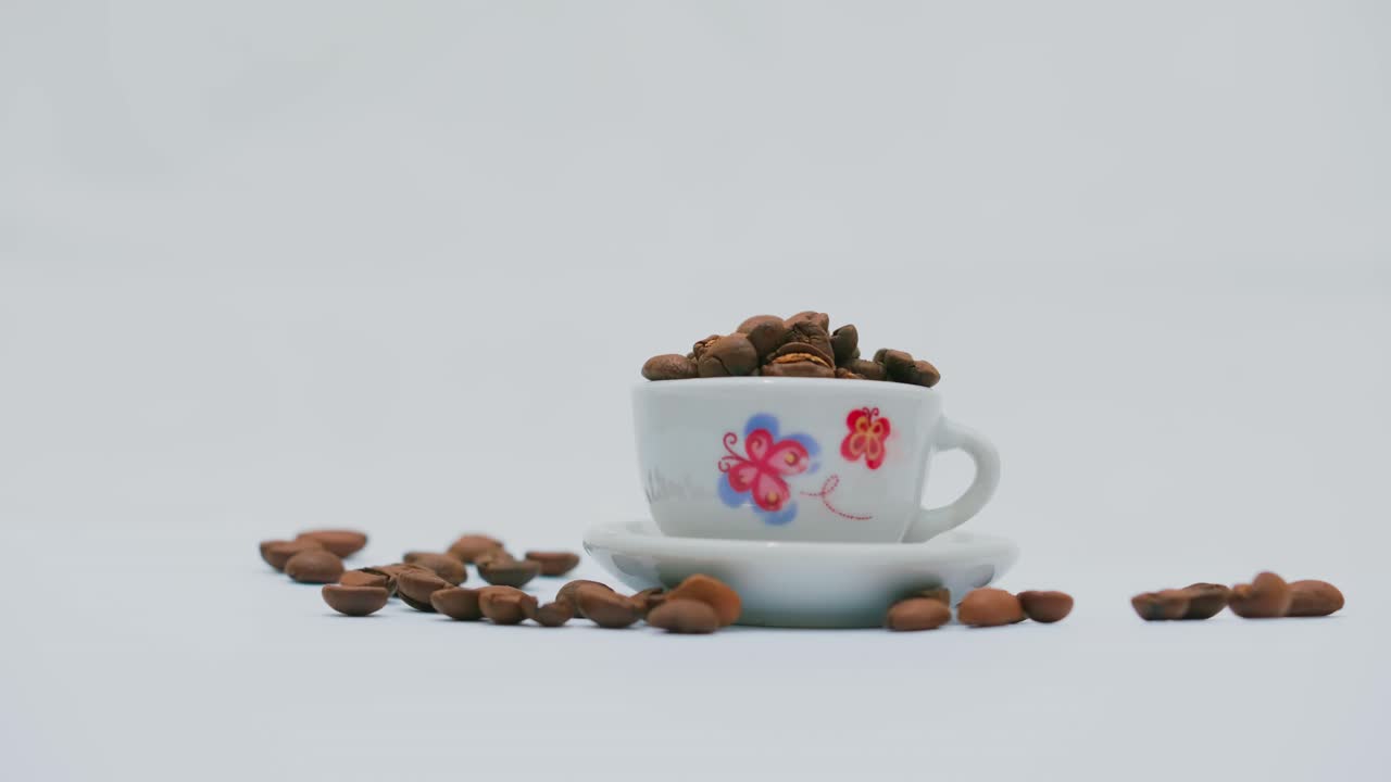 foto de estudio: granos de café dentro y alrededor de una taza blanca y plato con diseño floral