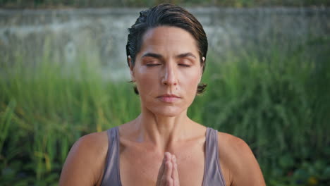 serene model namaste position greenery nature portrait. lady meditating closeup