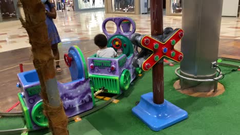2-jähriges-Afroeuropäisches-Baby,-Das-In-Einem-Einkaufszentrum-Mit-Einer-Elektrischen-Spielzeugeisenbahn-Fährt