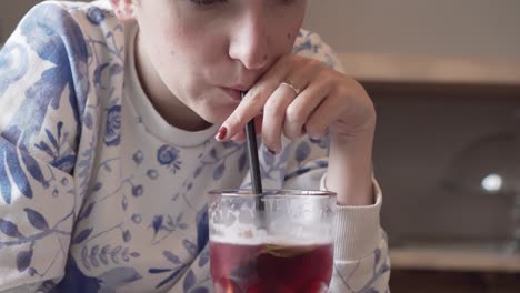 young caucasian girl drinking red lemonade with a plastic straw