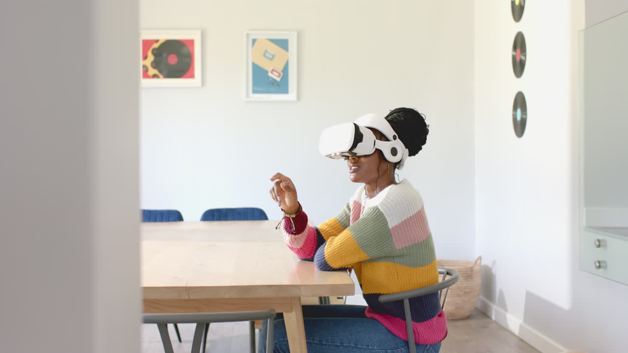 African American young woman wearing virtual reality headset, sitting at table at home, at home, cop