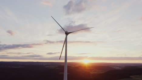 wind turbine at sunset over hills