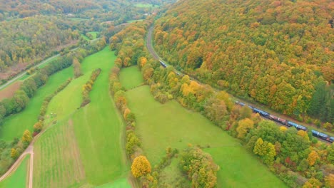 aerial drone shot of a freight train in vibrant autumn colours 4k