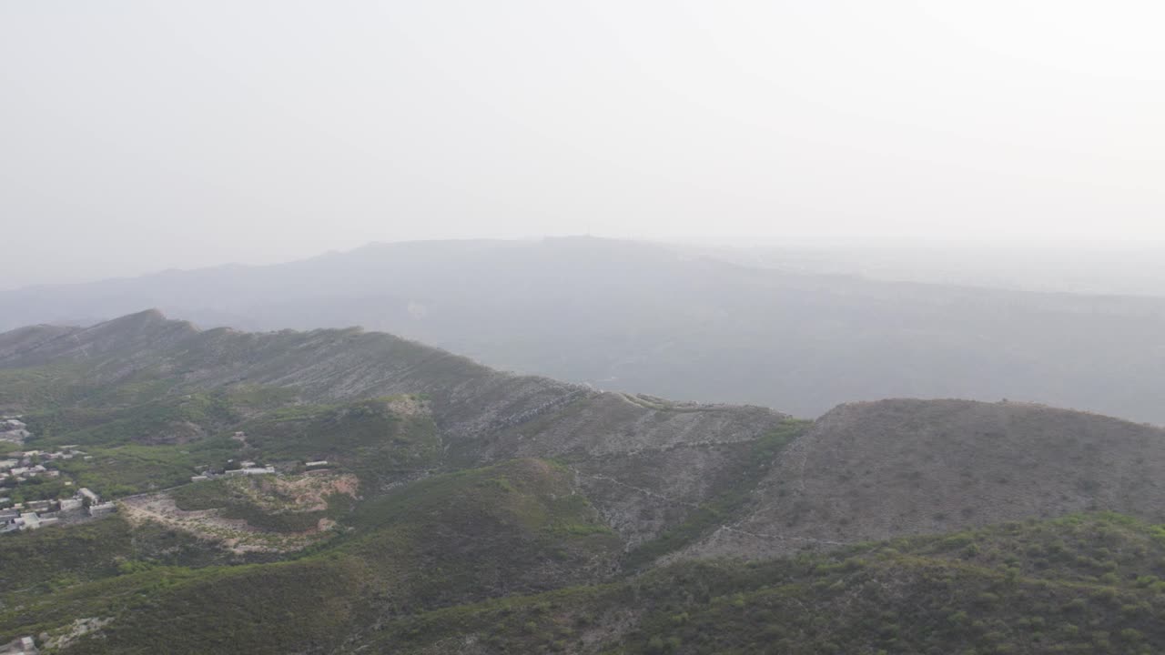 Aerial view of rocky ridges and sparse greenery in Kallar Kahar, Chakwal, under a hazy sky. Chakwal, Pakistan