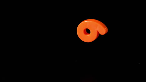 número seis naranja cayendo sobre fondo negro