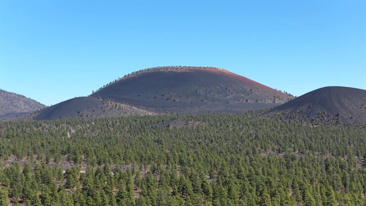 Ripresa aerea 4K con drone di un'antica foresta di pini ponderosa e colline di scorie vulcaniche vicino a Flagstaff, Arizona. Paesaggio selvaggio e panoramico del sud-ovest per il turismo di viaggio e il B-roll di marketing delle destinazioni.