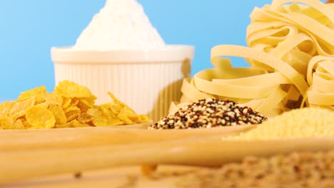 a variety of grains, pasta, and bread arranged on a table with a vibrant blue backdrop, showcasing diverse textures