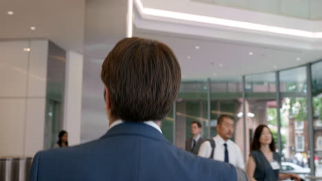 mature businessman walking to work in busy corporate office lobby