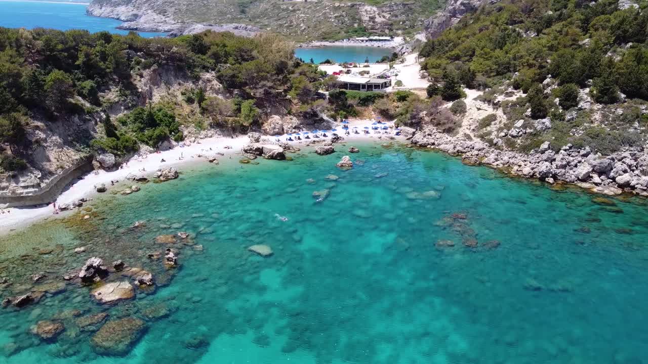 Cinematic aerial shot circling around a breathtaking beach in Greece during a beautiful sunny day