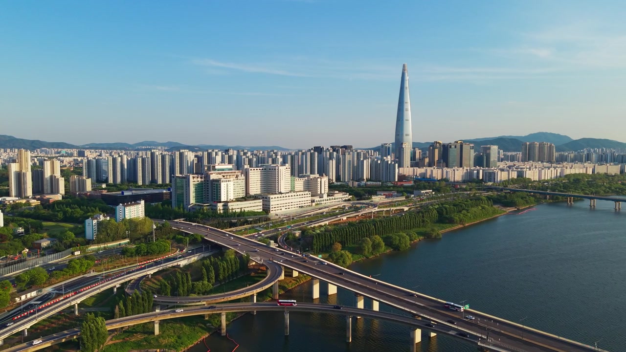 Ripresa con drone in avvicinamento sopra il fiume Han verso la Lotte World Tower e lo skyline della città di Seul all'ora d'oro