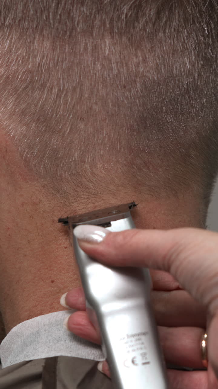 Close-up of Hairdresser Trimming Man's Neck Hair with Electric Clippers