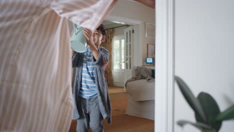 niño feliz persiguiendo a su madre con un bote de riego jugando a atrapar corriendo por la casa madre disfrutando de un juego divertido con el niño disfrutando de la mañana de fin de semana juntos 4k imágenes